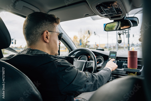 A man uses a smartphone installed in the holder while driving a car photo