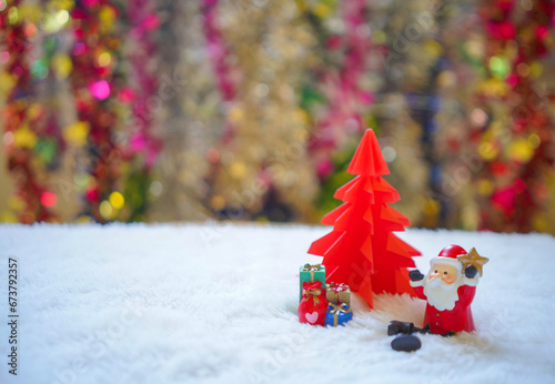 Sata sitting on white snow with group of gifts  in front of red origami Christmas tree waiting for funny festival, Christmas and New Year concept. photo