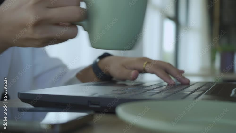 Young woman's hands using laptop working on table in the morning with hot coffee Young woman's hands using laptop working on table in the morning with hot coffee