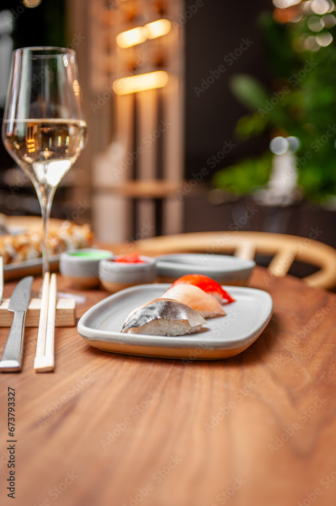 Nigiri set: mackerel, sea bass, salmon on a plate on a table in a sushi bar