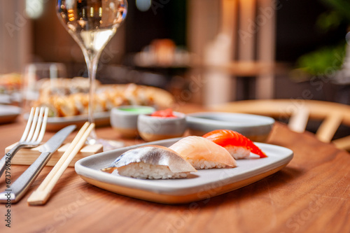 Nigiri set: mackerel, sea bass, salmon on a plate on a table in a sushi bar photo