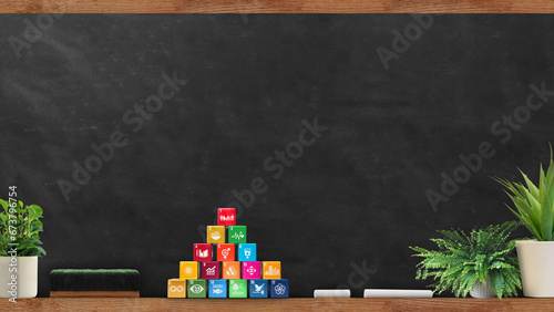 Sustainable Development global goals cube set besides of Blackboard in a School class room. Sustainable Education concept. Corporate social responsibility. 