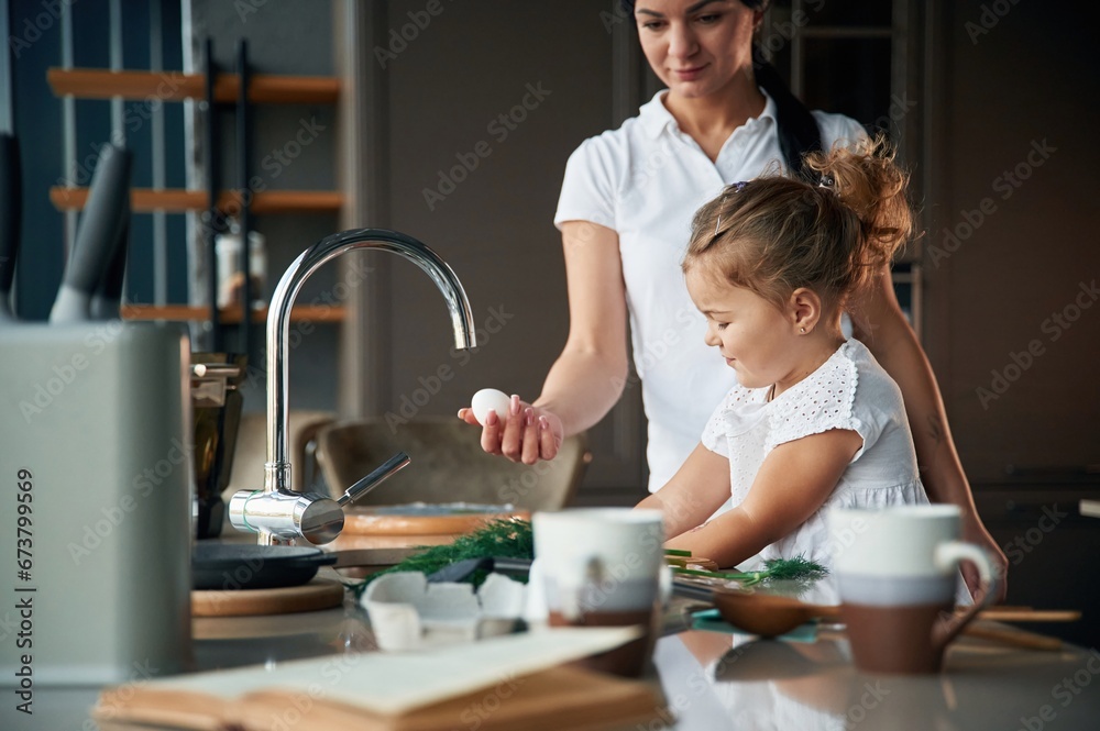 Process of learning. Mother with her daughter are preparing food on the kitchen Process of learning. Mother with her daughter are preparing food on the kitchen