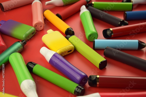 Set of multicolor disposable electronic cigarettes on a red background.