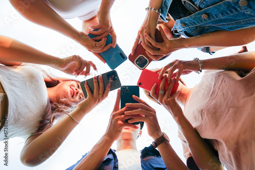 Image of a group of young Asian people laughing together and using their phones