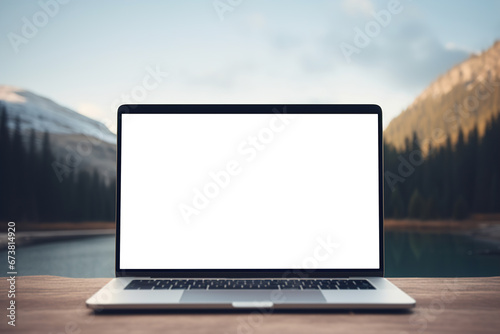 Laptop mockup with blank screen for advertising on a wooden table against a background of lake and mountains, outdoors