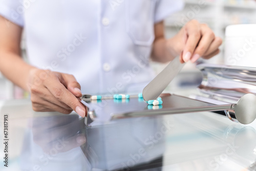 Close up of female pharmacist counting and arrange pills on qualified stainless counting tray with spatula in pharmacy. Pharmacist prepare medication in stainless tray by prescription at drugstore.