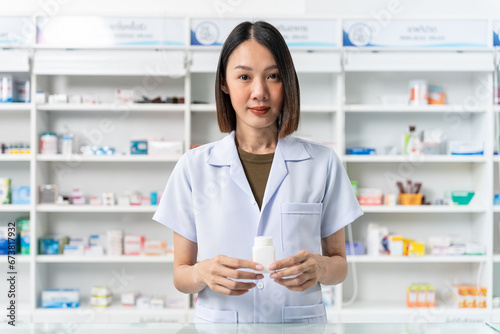 Happy beautiful asian female pharmacist wearing lab coat standing and holding pill bottle, She looking at camera feels good, trustworthy and proud of his work in the pharmacy drugstore. Free Download Happy beautiful asian female pharmacist wearing lab coat standing and holding pill bottle, She looking at camera feels good, trustworthy and proud of his work in the pharmacy drugstore. - GFXLoad