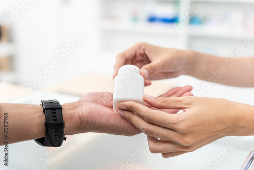 Close up hands of female selling pharmacist and male customer buying medicine in the pharmacy drugstore, hand over pills bottle of medicine from hand to another hand charge. photo