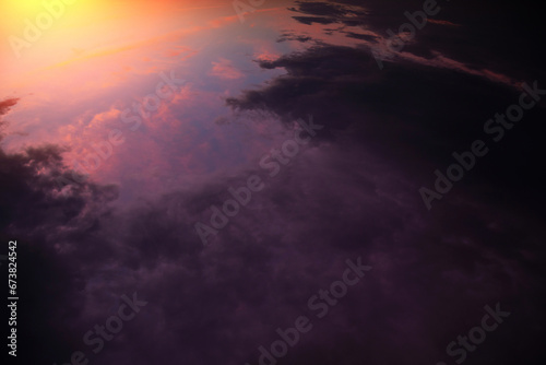 Sunrise  sunset above planet Earth from space  epic storm sky with dark violet pink clouds  orange yellow sun and sunlight. View from space over thunderstorm rain clouds