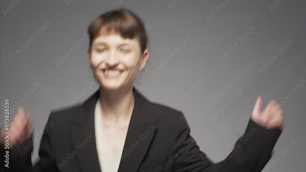Cute girl in a suit against gray background. Happy young business woman dancing. Cute girl in a suit against gray background. Happy young business woman dancing.