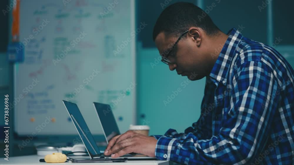 African American IT specialist typing programming code, testing software at work