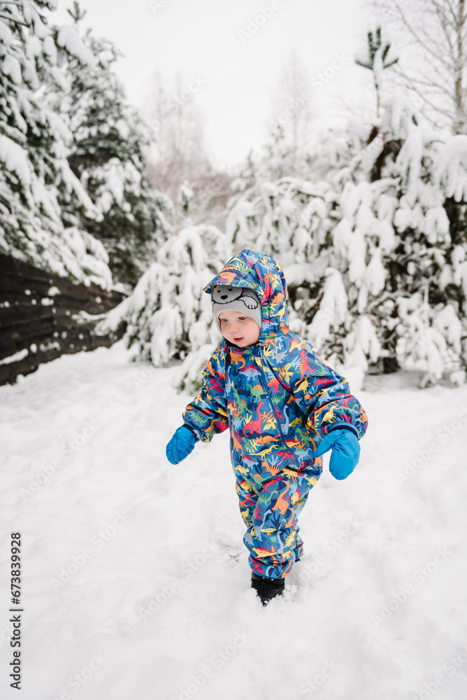 Little child in blue winter clothes having fun. Kid wearing warm hat walking in winter park in holidays. Toddler in mountain country in snowy forest. Baby boy playing snow among snowdrifts closeup. Little child in blue winter clothes having fun. Kid wearing warm hat walking in winter park in holidays. Toddler in mountain country in snowy forest. Baby boy playing snow among snowdrifts closeup.