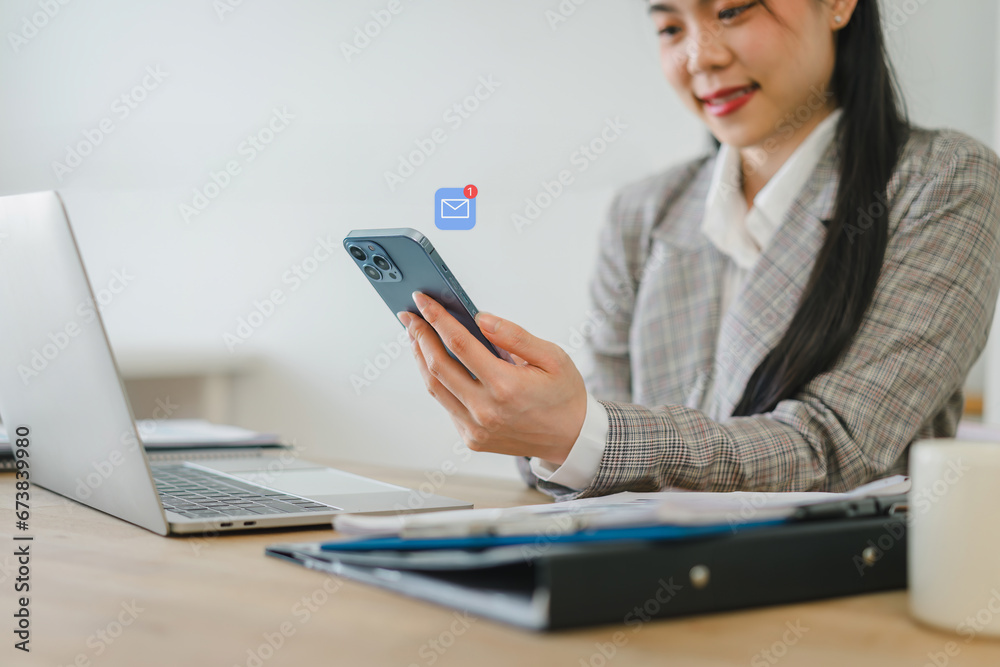 Young businesswoman using smartphone to receive a new email message alert in the office. Young businesswoman using smartphone to receive a new email message alert in the office.