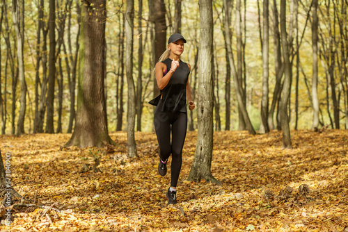 Sporty young woman running in forest in morning. Concept of sport, healthy lifestyle. Autumn season
