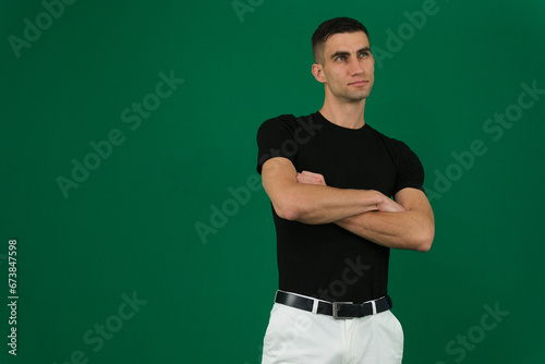 fold hands on chest man. emotions of a handsome man guy on a green background chromakey close-up dark hair young man