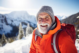 Elderly man wearing bright orange jacket hiking in winter mountains
