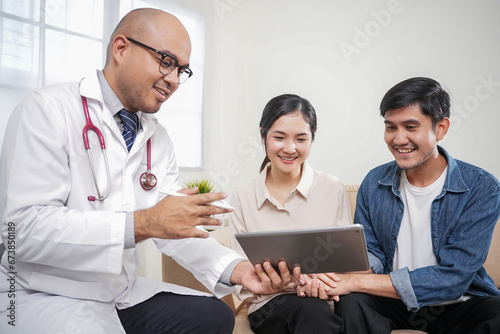 Asian couple discussing infertility problems with a handsome doctor, They feeling happy and holding hand together when received good news from the doctor.