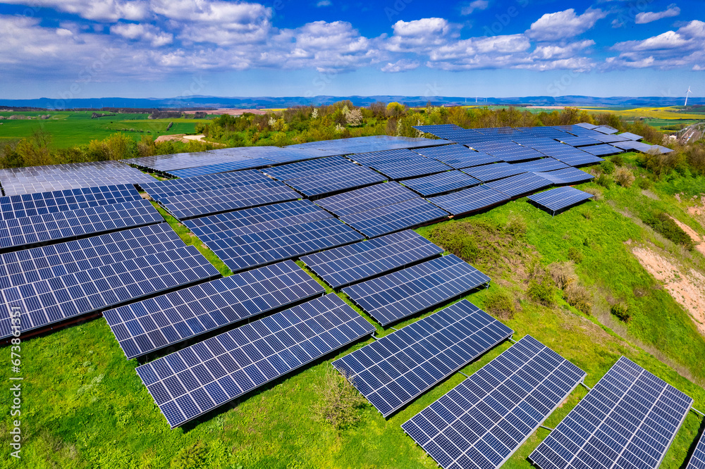Flying over a solar farm with photovoltaic panels converting solar power to electricity for green energy on agricultural land