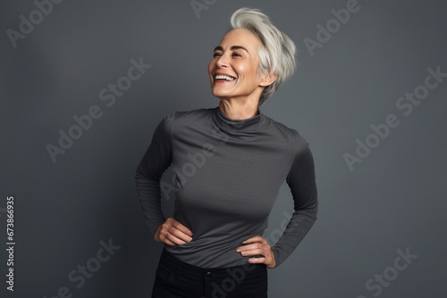 Graceful Aging: A Smiling and Happy Mature Lady Graces a Plain Grey Background, Exuding Contentment, Cheerfulness, and the Inner Peace of Retirement