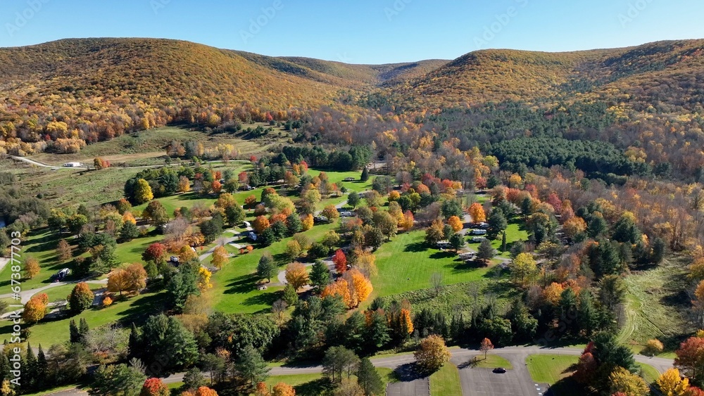 Camping in the great outdoors in nature in campgrounds for RVs and tents on a green pastures below a mountain range in Autumn Fall colors in Ives Run Campground in Pennsylvania countryside