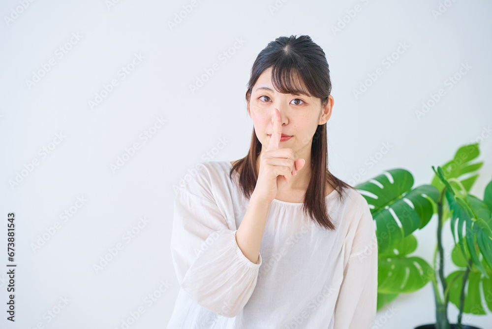 人差し指を口に当てるポーズをする若い女性