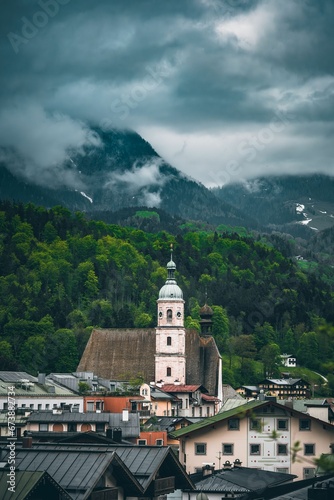 Vertical of a church tower in Berchtesgaden, Germany in green mountains on a cloudy day