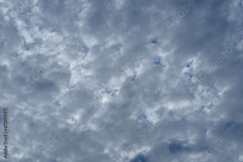 Thick clouds weave a heavy tapestry above, with glimpses of blue peering through a monochrome mosaic.