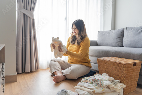 Pregnant asian woman getting ready for the maternity hospital preparing and planning baby clothes for new baby of pregnancy packing for maternity hospital at home photo