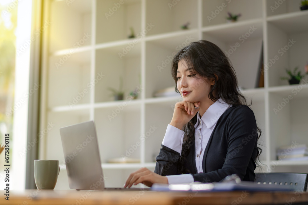 Freelance Asian woman sitting and working on laptop. Thinking, planning and focusing on the task. Freelance Asian woman sitting and working on laptop. Thinking, planning and focusing on the task.