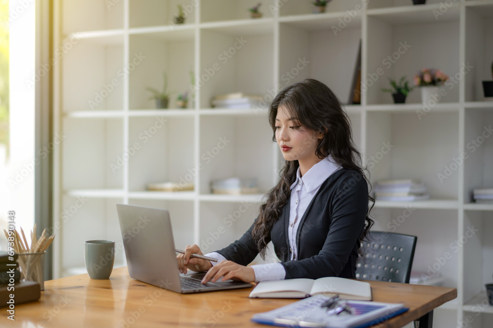 Freelance Asian woman sitting and working on laptop. Thinking, planning and focusing on the task. Freelance Asian woman sitting and working on laptop. Thinking, planning and focusing on the task.