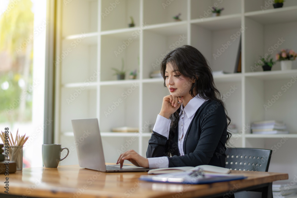 Freelance Asian woman sitting and working on laptop. Thinking, planning and focusing on the task. Freelance Asian woman sitting and working on laptop. Thinking, planning and focusing on the task.