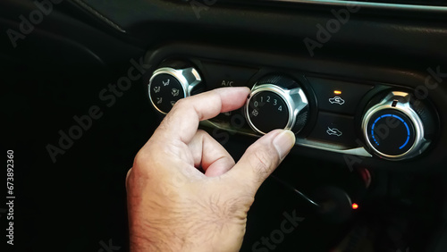 Hands man turning circular switch air condition fan for adjust cooling  system interior car automobile, transportation and vehicle concept, close up. © surasak