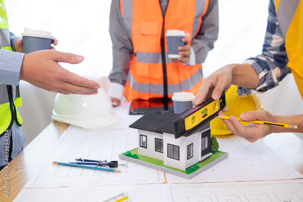Architects and construction engineers meet to discuss blueprints of building structures in order to calculate the completion of the construction project. Real estate construction business concept.