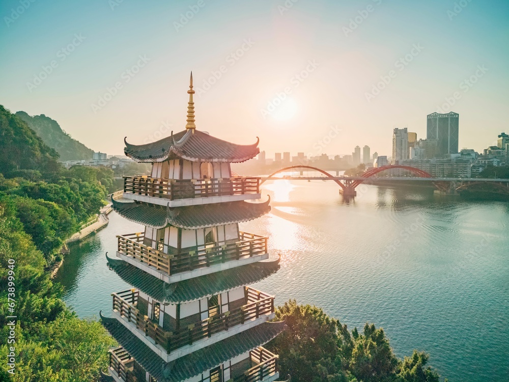 Obraz premium Setting sun shines on a tower by the river in Liuzhou, Guangxi, China, Asia