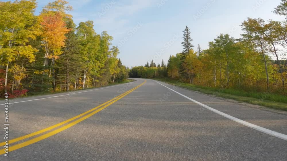 POV from the front of a vehicle driving quickly along a paved two lane road that is surrounded by trees with autumn colors.
POV from the front of a vehicle driving quickly along a paved two lane road that is surrounded by trees with autumn colors.