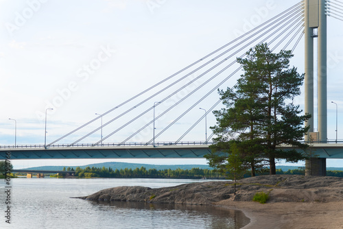 A calm view of a bridge in the city of Rovaniemi. Traveling north, outdoor recreation, polar circle, tourism in Lapland. Bridge with lumberjack candle. River near the forest. Quiet place for relax photo