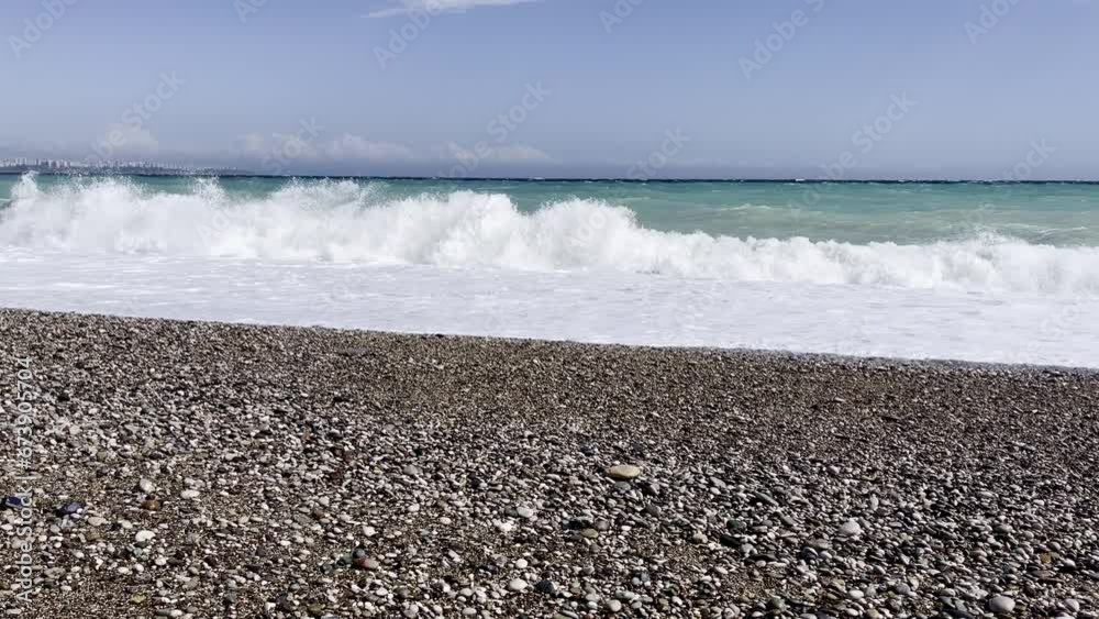 Powerful sea waves are crashing on coast. Waves splash on the beach with pebbles during a storm. Storm at sea. Powerful sea waves are crashing on coast. Waves splash on the beach with pebbles during a storm. Storm at sea.