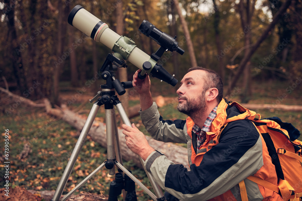 Man using telescope for bird and animal watching in nature.