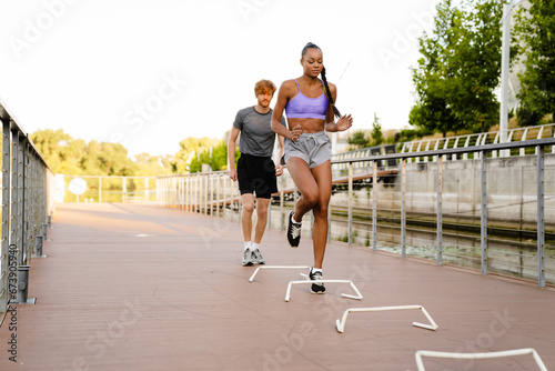 Active man and woman doing workout outdoors on city bridge