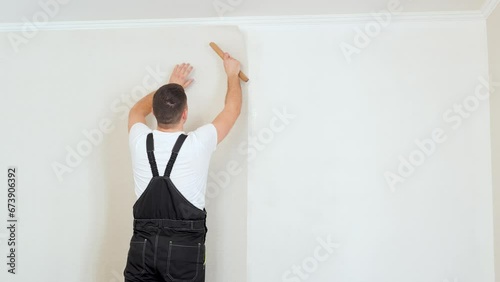Man glueing wallpapers at home, stylish wallpaper sheet. Space for text
