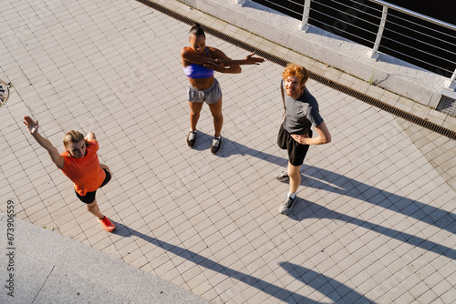 Top view group of three fitness people doing workout together outdoors on bridge