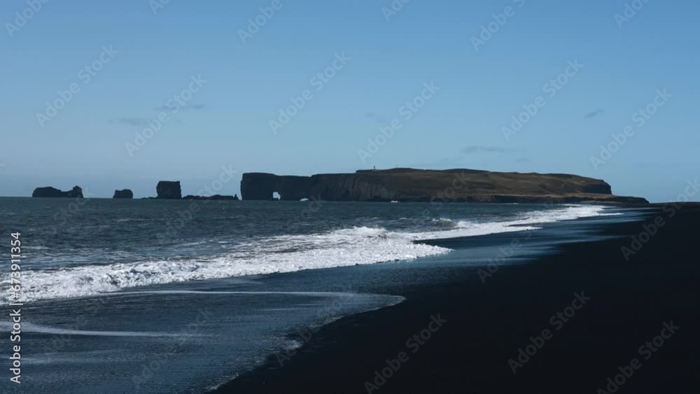 Beauty of Iceland's Black Sand Beach. Rugged landscapes and volcanic serenity. Dyrhólaey promontory in the distance. White waves roll out over the black volcanic sand. Reynisfjara beach. Beauty of Iceland's Black Sand Beach. Rugged landscapes and volcanic serenity. Dyrhólaey promontory in the distance. White waves roll out over the black volcanic sand. Reynisfjara beach.