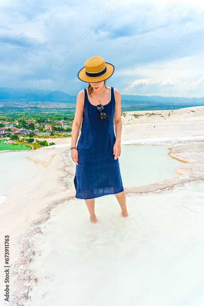 Tourist girl in dress with hat in Natural travertine pools and terraces in Pamukkale. Cotton castle in Turkey. Woman in pamukkale.