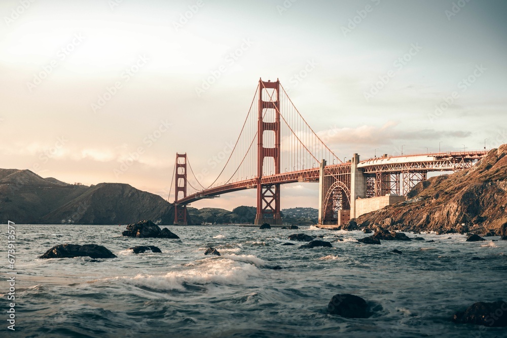 Obraz premium Golden Gate Bridge spanning over a tranquil body of water during a mesmerizing sunset