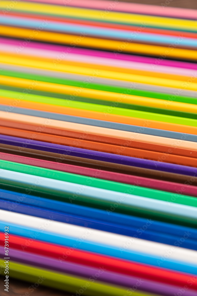 Set of watercolor pencils on brown wooden. Side view, selective focus