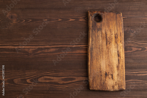 Empty rectangular wooden cutting board on brown wooden. Top view, copy space