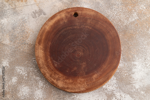 Empty round wooden cutting board on brown concrete. Top view