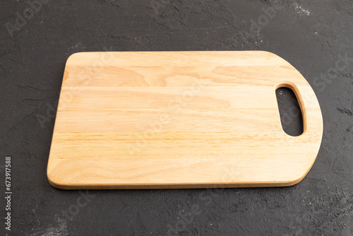 Empty rectangular wooden cutting board on black concrete. Side view