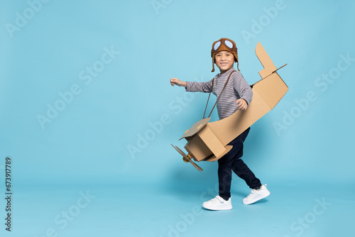 Asian little boy aviator playing with cardboard airplane isolated on blue sky background, Kid toy diy concept